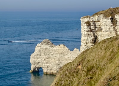 Blue sea white rock strata during the day
